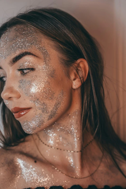 woman looking up with silver glitter all over her face