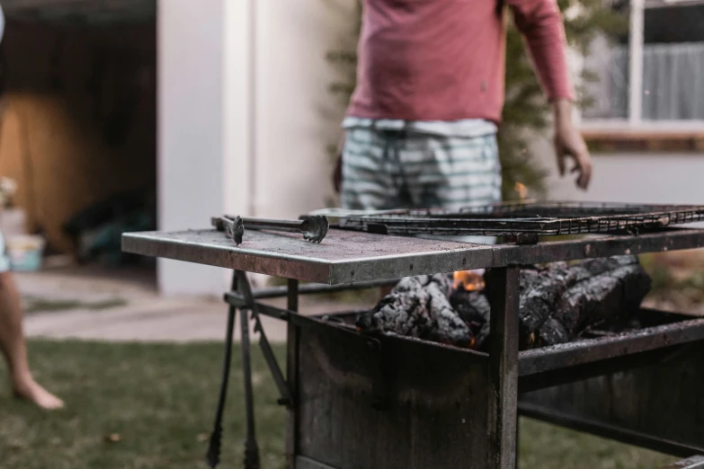 a man holding an object in his hand near a barbecue grill