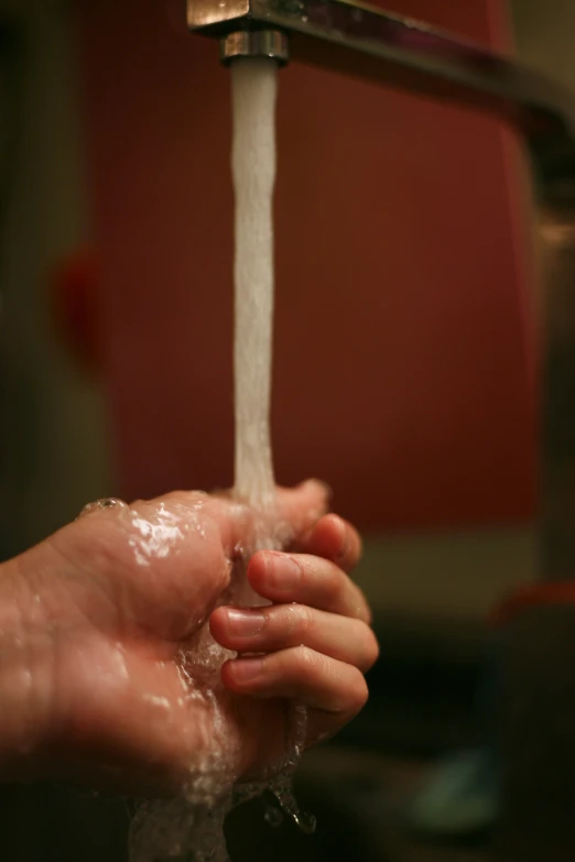 the hands are washing their hands under a faucet