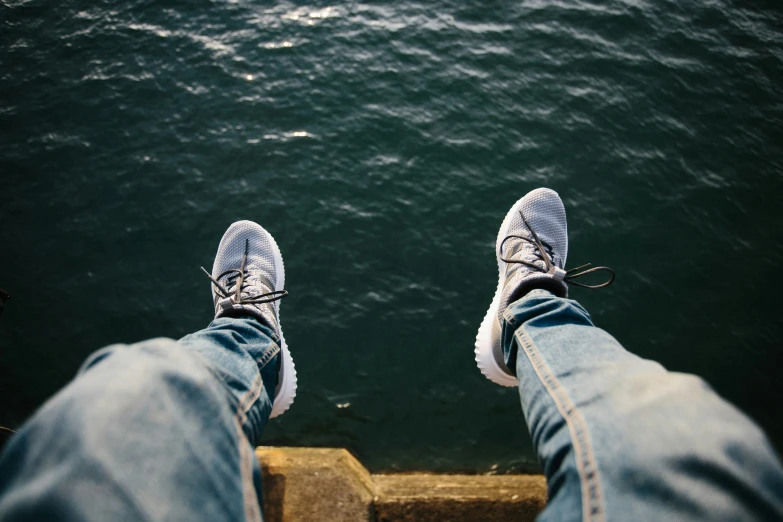 feet with shoes standing on a wall with water