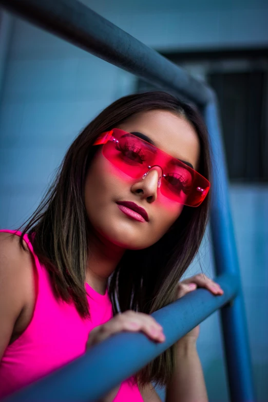 a woman in pink wearing sunglasses leaning against the railing