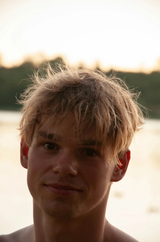 young man posing in front of the water with his hair combed back