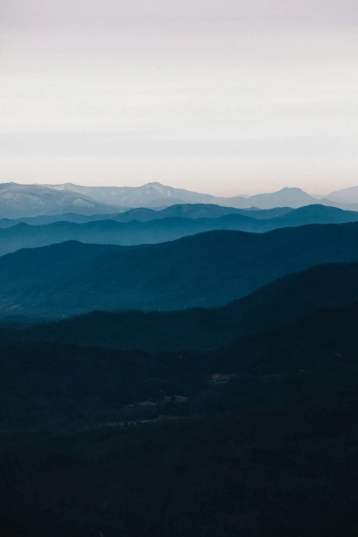 a view of mountains covered in mist at sunrise