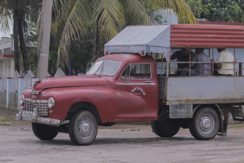 the old truck is carrying people on a street