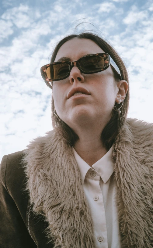 a woman wearing sunglasses staring into the sky