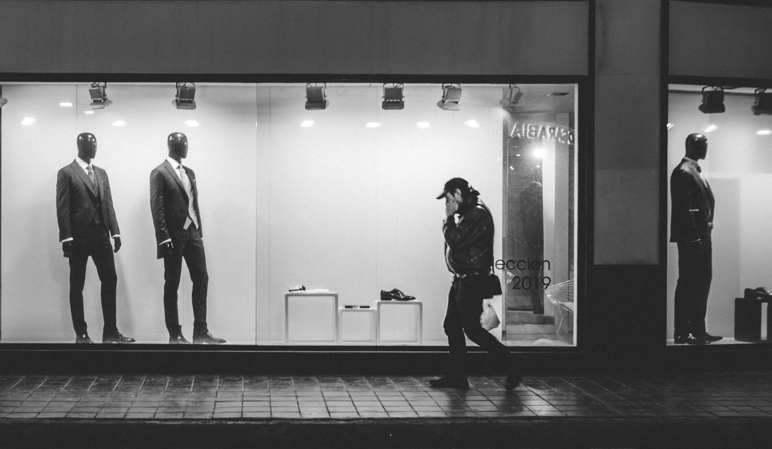 a man walking in front of a store with mannequins