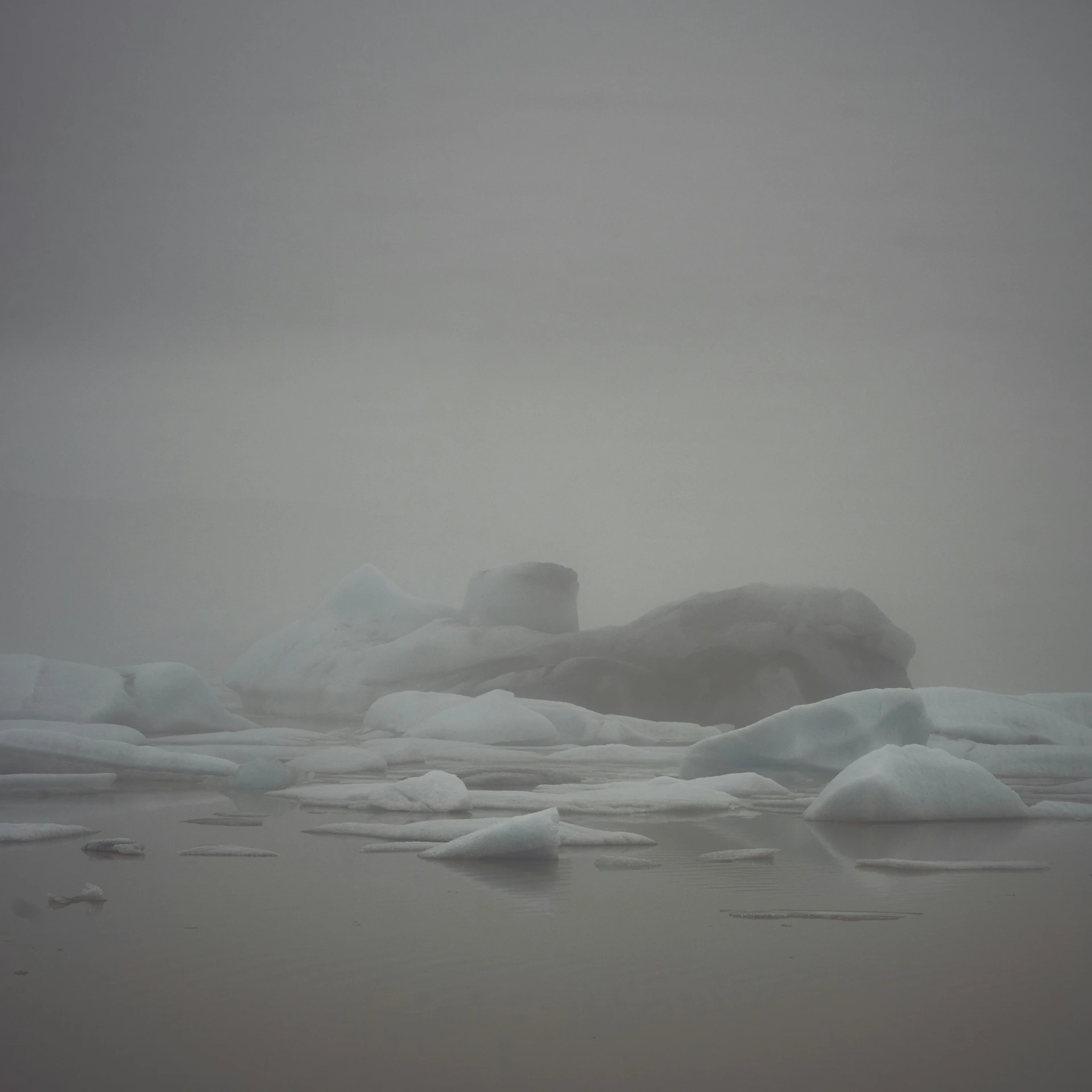 an ice covered lake in a foggy landscape