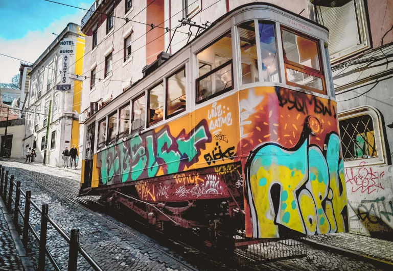 an old tram covered in graffiti near a building