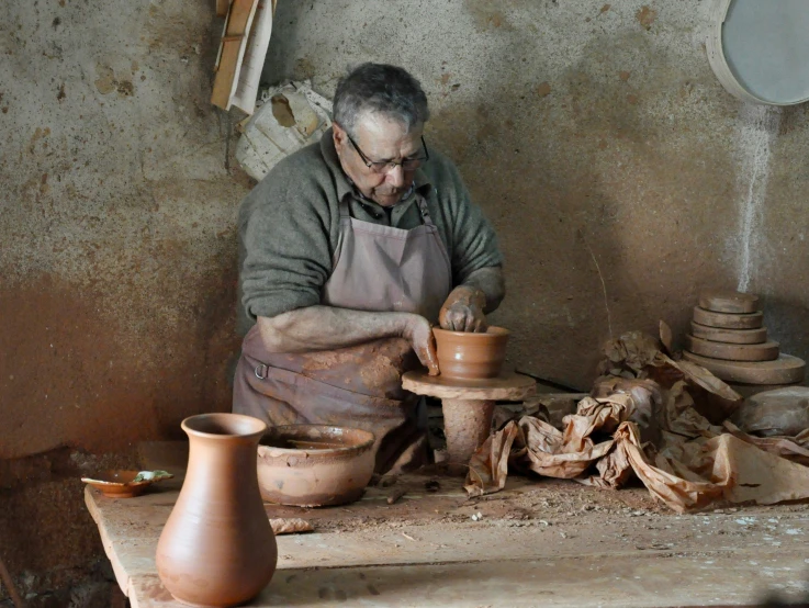 man making pots from clay on workbench