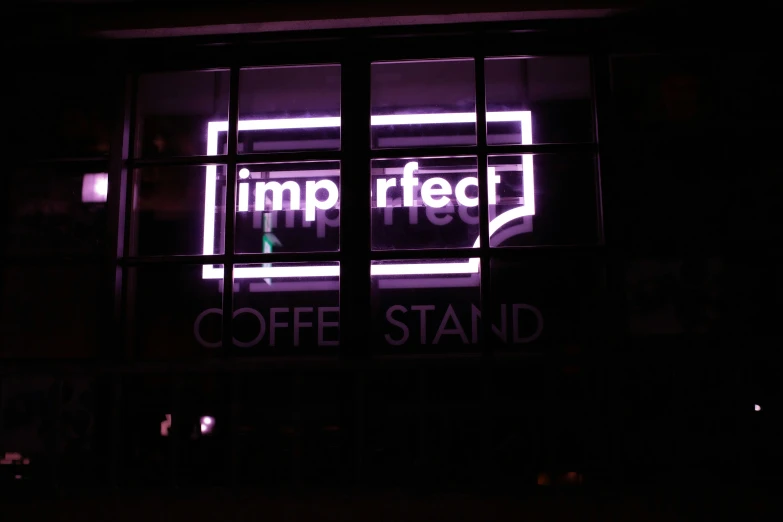 a purple sign on a window in the dark