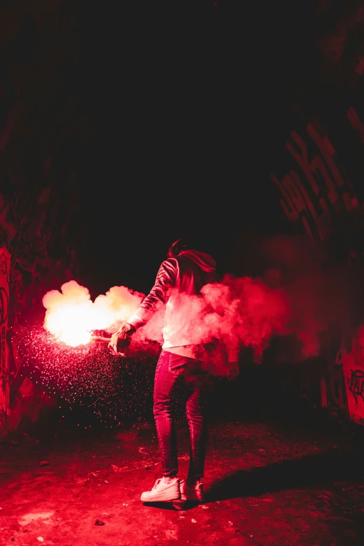 a man standing in the middle of an alley way with colored smoke