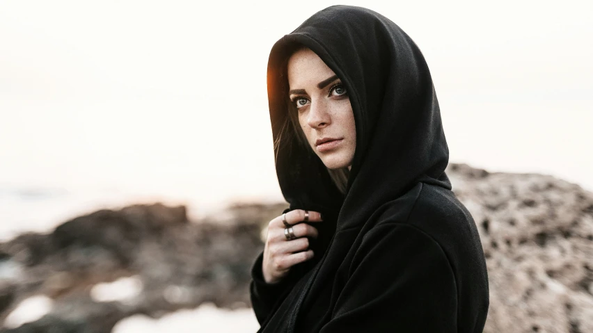 a man standing outside wearing a black hoodie