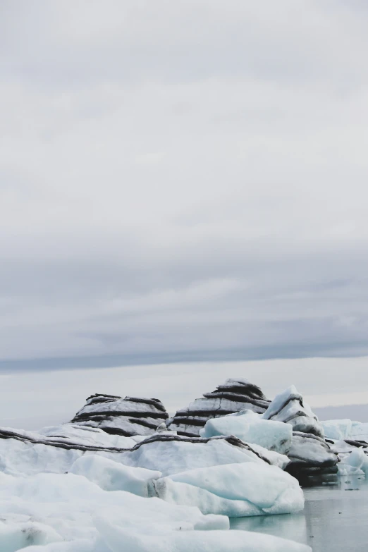 a large group of rocks covered in snow next to water