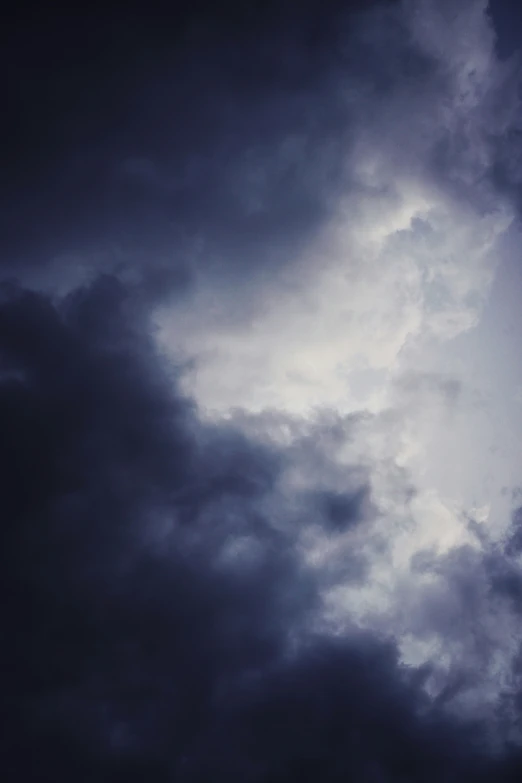 a jet airliner flying over clouds on a cloudy day