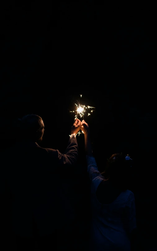 man and woman holding up their hands to see the sparkler