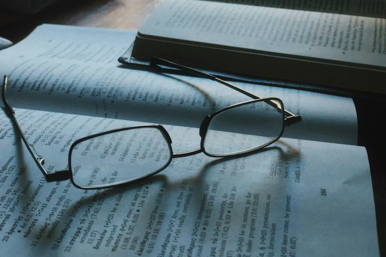 the glasses are lying on the table next to the book