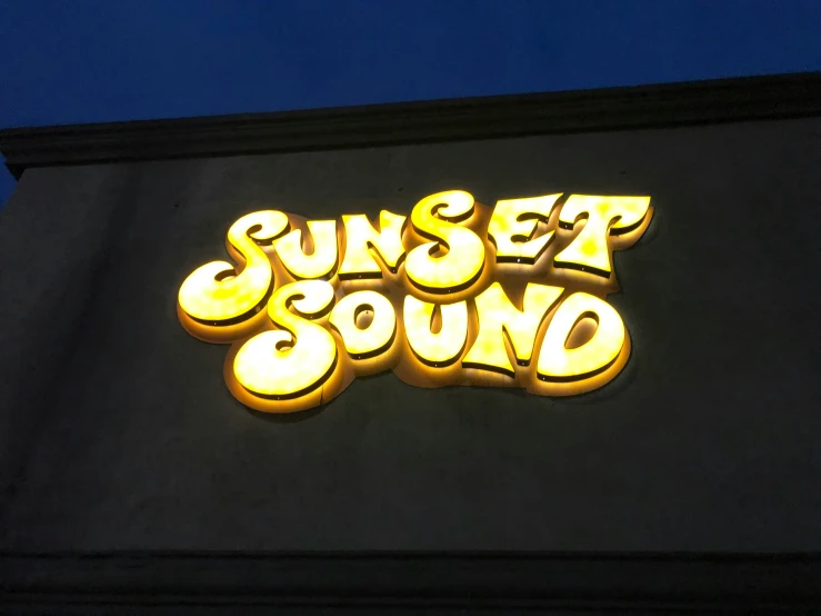 a neon sign reading sunset sound above a building