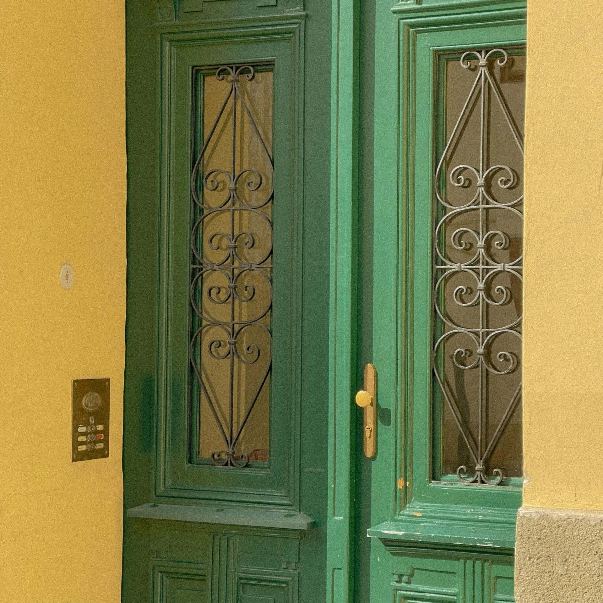 an ornate iron door on a yellow and green house