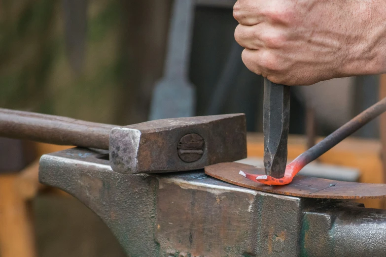 two hands are holding tools to an old rusty iron pipe