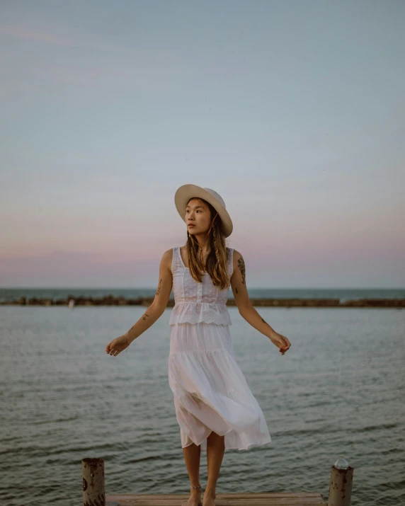 a girl wearing a hat is standing on a pier