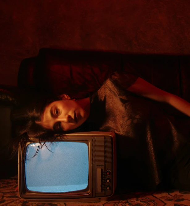 a person lying on the ground beside an old fashioned television