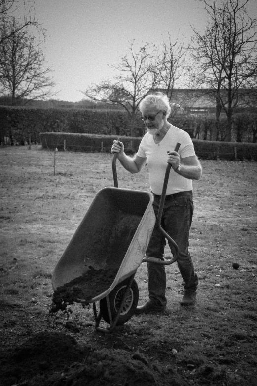 old lady is hing a wheelbarrow and pulling it to the park