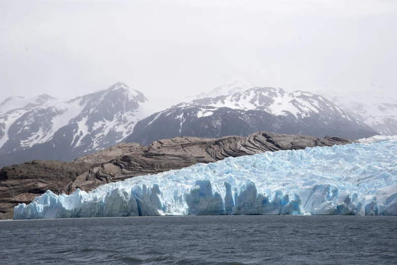 a glacier wall in front of mountain peaks