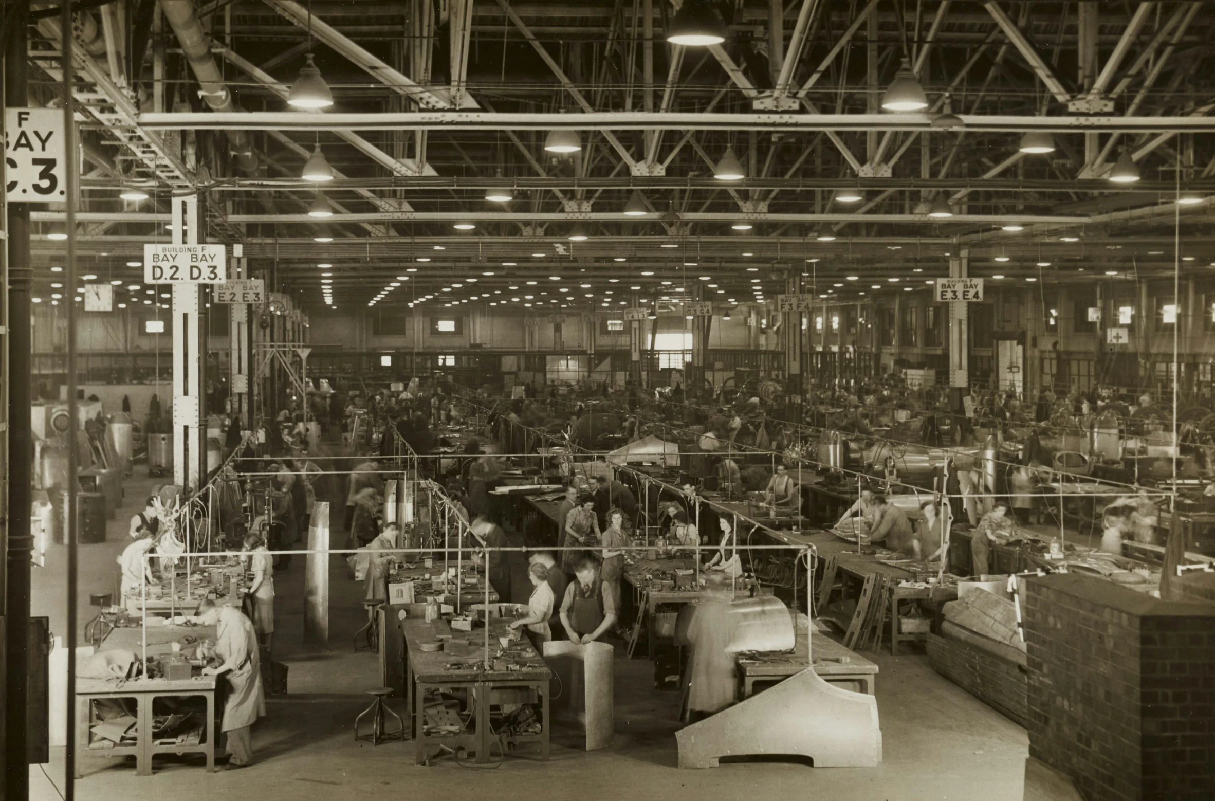 a black and white picture of a factory with people standing around