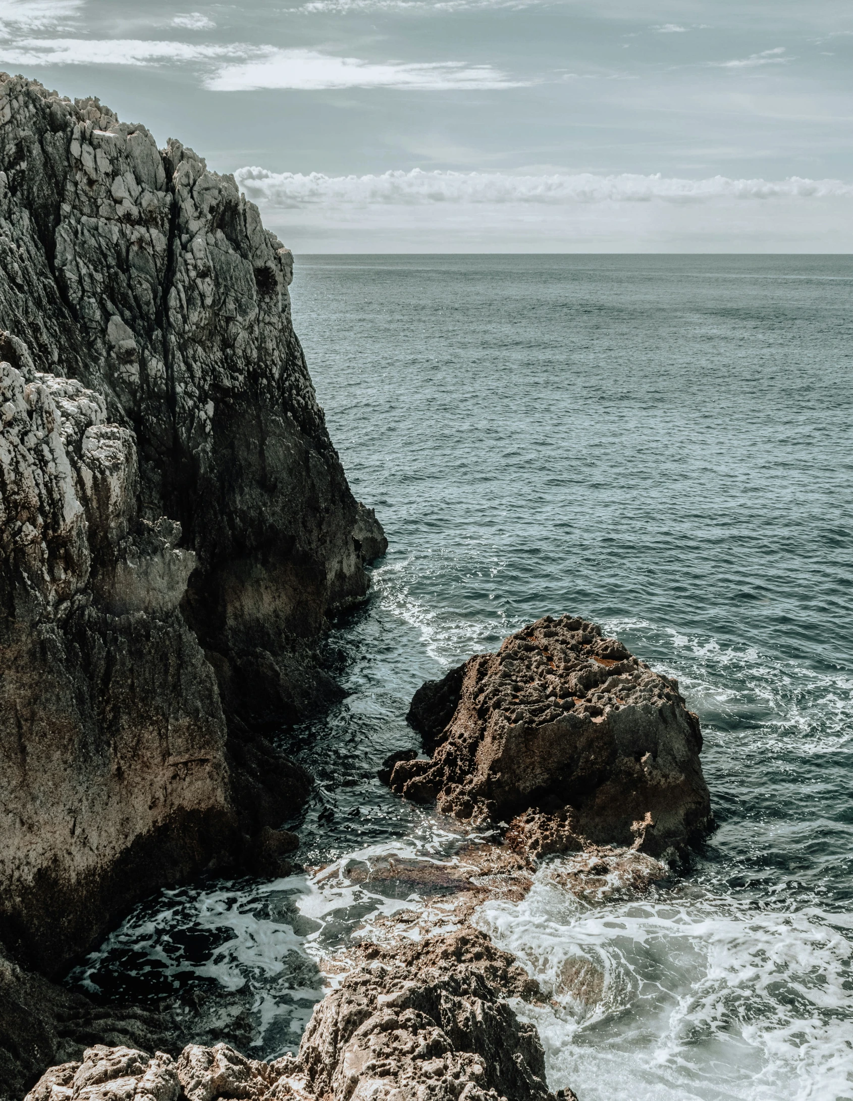 an image of a rocky shoreline with waves crashing onto the rocks