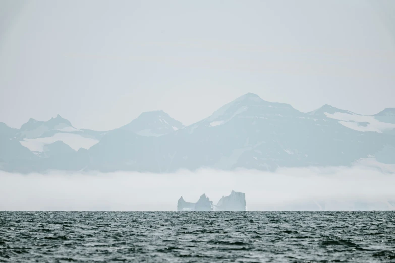 mountains on a gray day with fog moving through the water