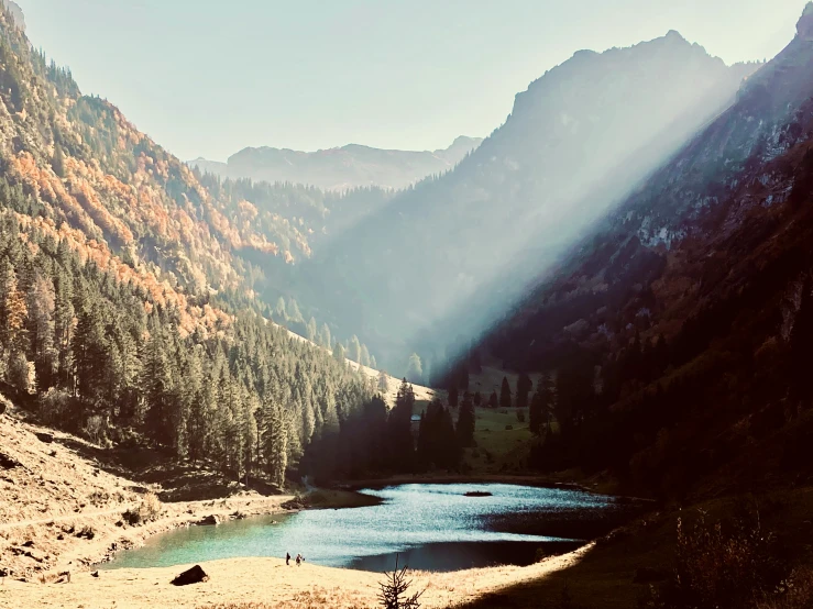 a view of mountains with water and a few people in the dirt