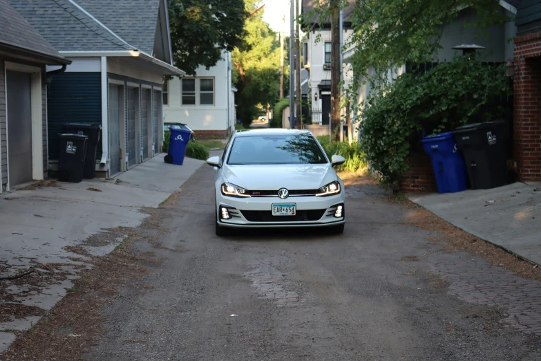 a white car driving down a street past tall buildings