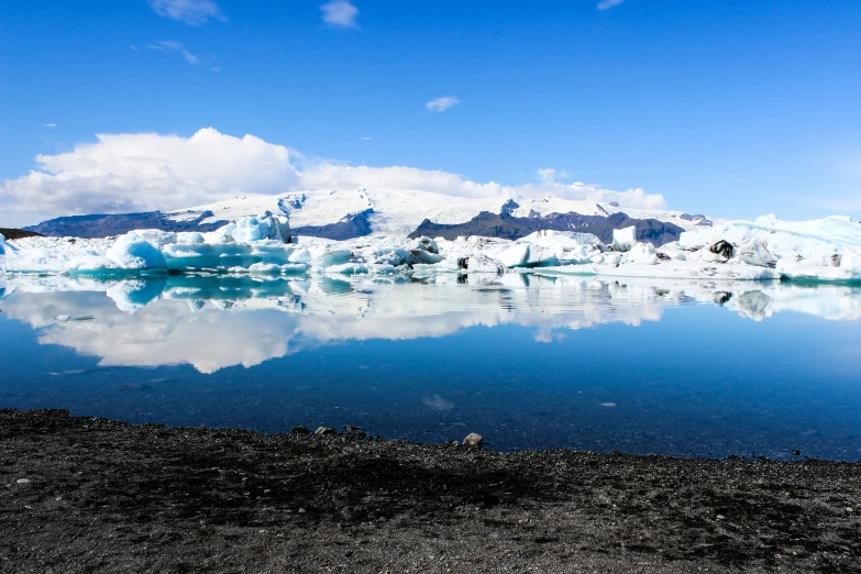 a group of mountains near a glacier with a large body of water in the foreground