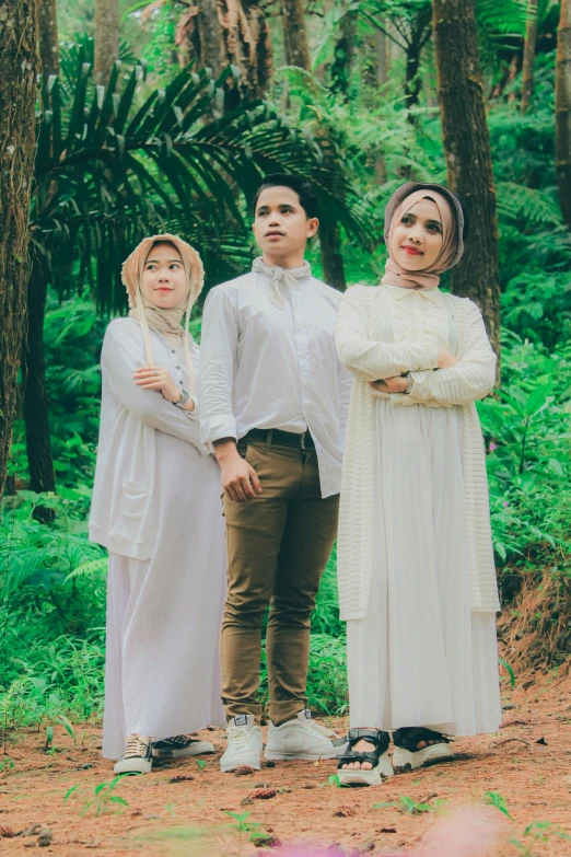 a family standing by some tall trees in the forest