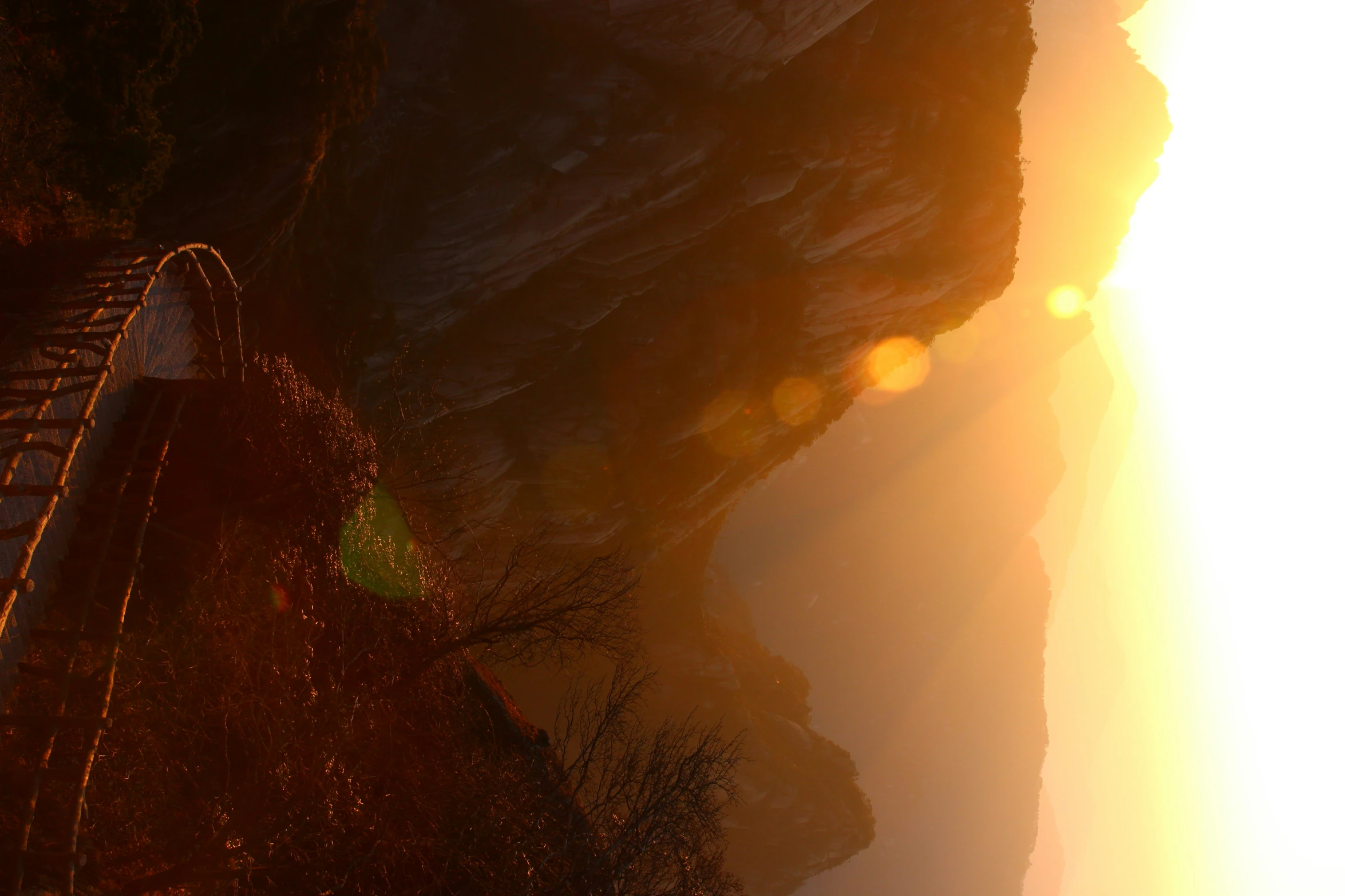 sunlight shining brightly in the mountains, over a path leading to a cliff