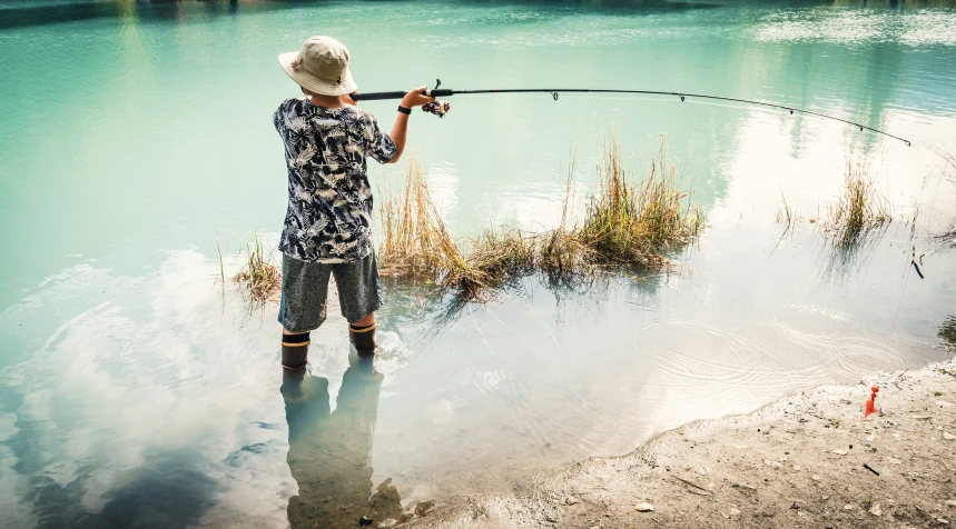 a  is standing in the water while holding his fishing rod