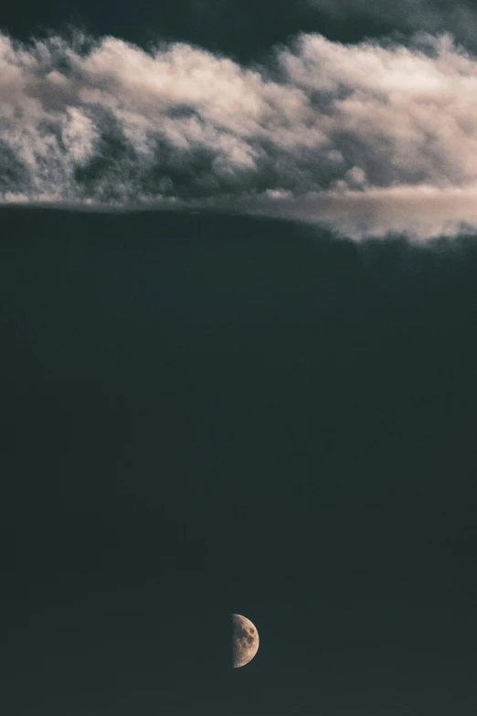 a distant crescent sits under the cloudy sky