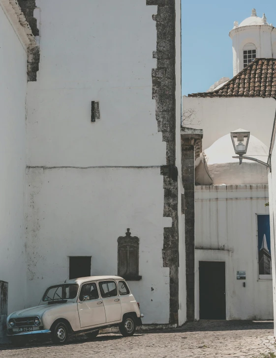 a car parked next to a white building on the side of a road