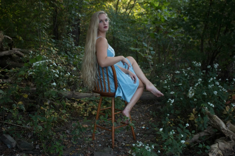 woman with long blonde hair sitting on chair in wooded area