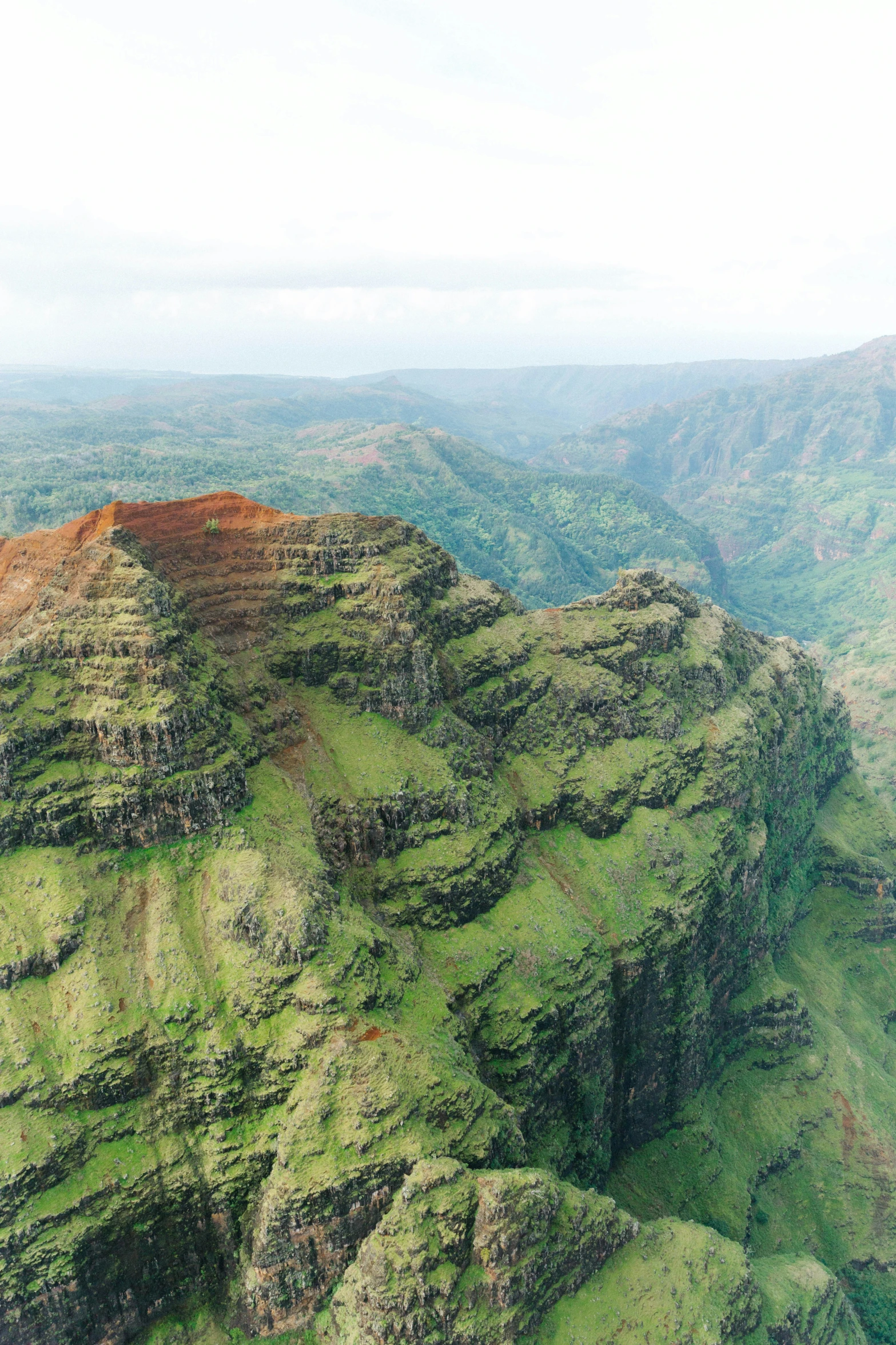 an aerial view of lush green mountains and cliffs