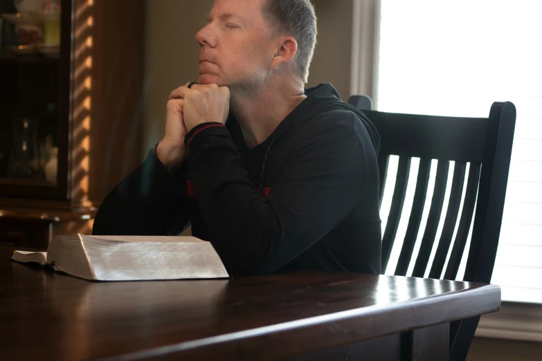 a man is sitting at a desk and leaning his elbows