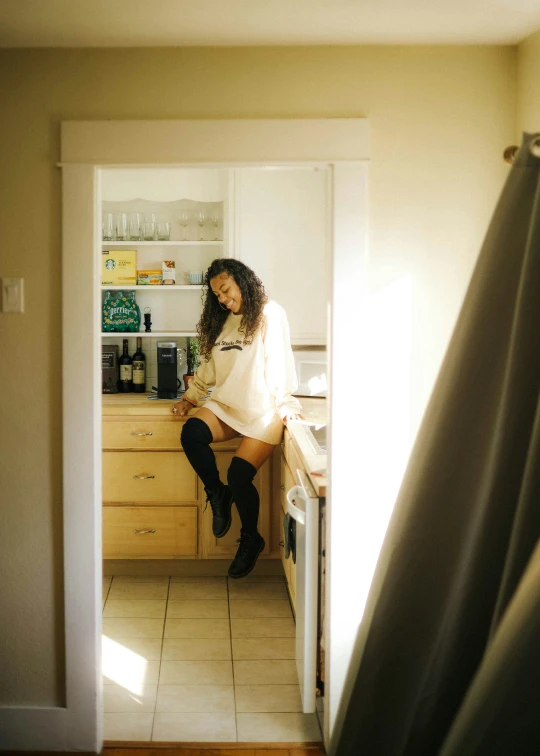 a woman sitting at the kitchen counter with a sink