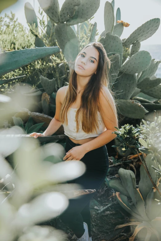 a young lady is standing among cactus plants