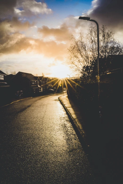 the sun sets behind some street lights with rain on the ground