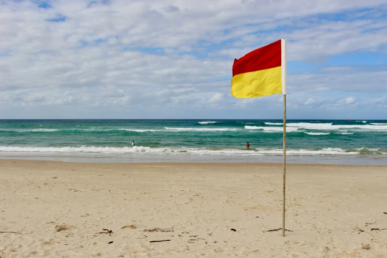 a large, yellow and red flag sitting on the beach