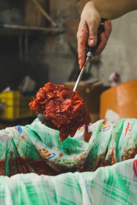 a person with a spatula scooping tomato into someones face