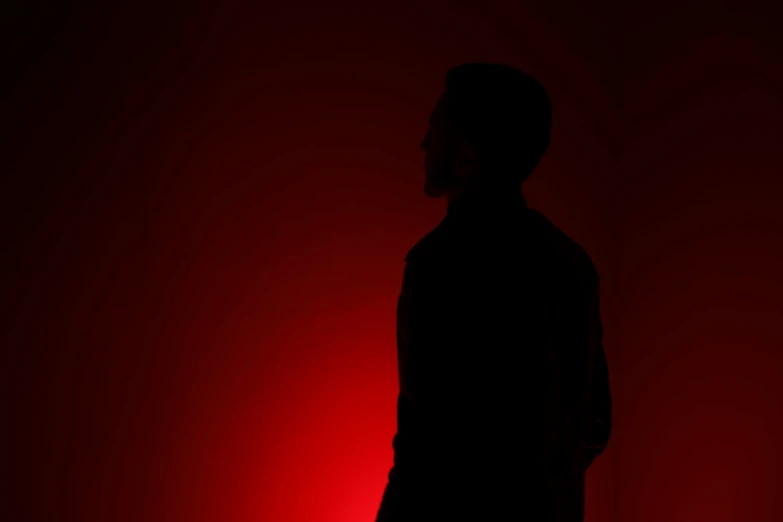 a man standing by a red wall in front of the camera