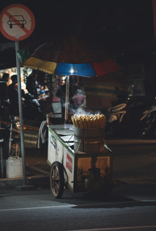 an outdoor vendor selling food on a street at night