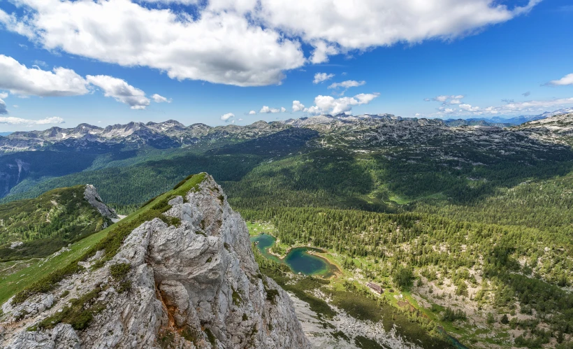 the top of a rock in the wilderness, with mountains and a body of water