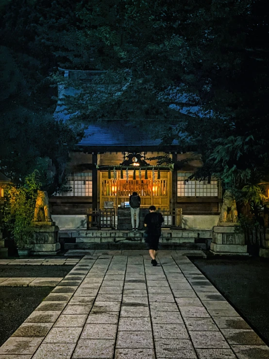 two people walking in the dark toward a building